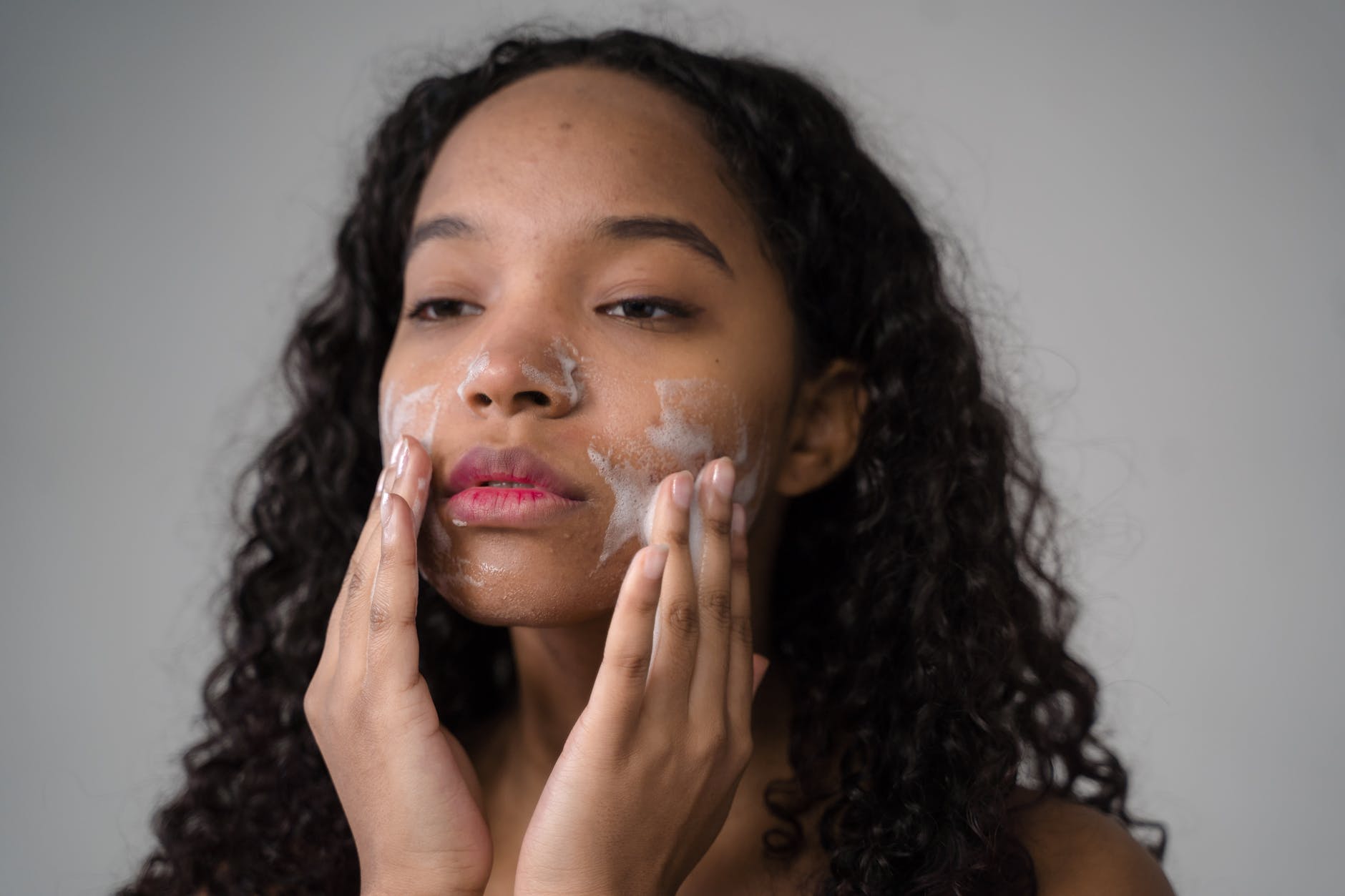 african american young girl washing face with facial foam