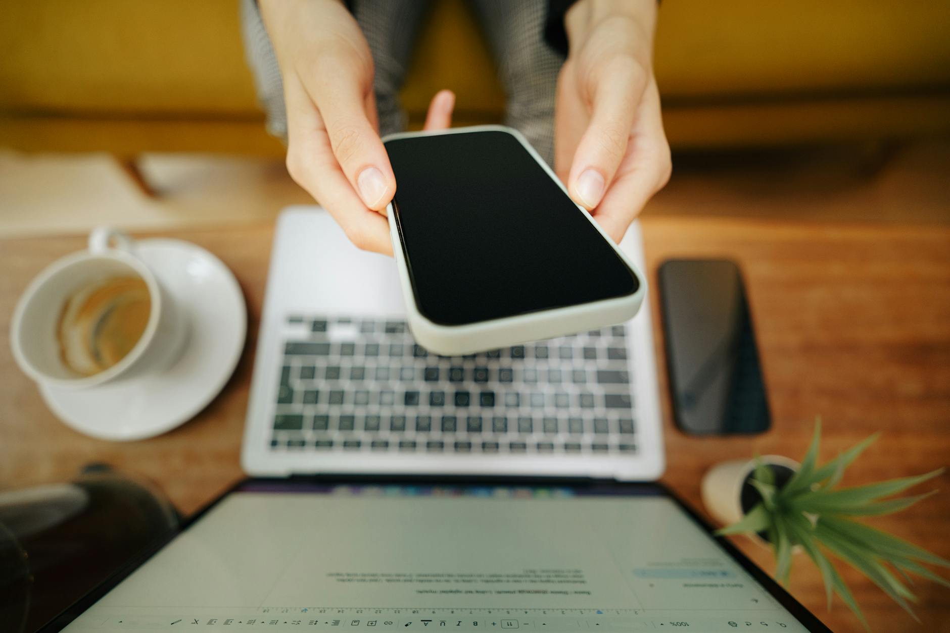 freelancer using smartphone and laptop in home office